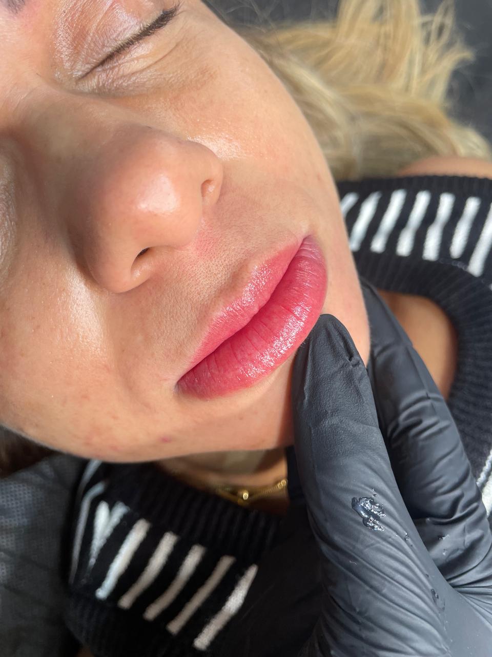 Lábios com Lips Glow recém-realizado, cor vermelha suave e contorno definido